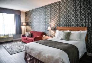 um quarto de hotel com uma cama e uma cadeira vermelha em Cambridge Hotel and Conference Centre em Cambridge