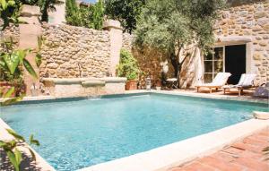 a swimming pool in a yard with a stone wall at Beautiful Home In Roujan With Wifi in Roujan
