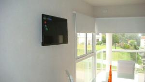 uma televisão de ecrã plano pendurada numa parede numa sala de estar em Pinamar Alquilo Depto A 150 Mts Del Mar em Pinamar