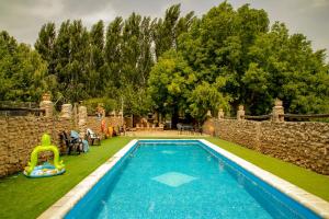 a swimming pool in a yard next to a stone wall at Apartamentos Rurales Labrador in Arbuniel +55 photos