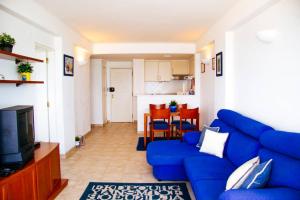 uma sala de estar com um sofá azul e uma cozinha em Panoramic Beach View Apartment (T2) in Caparica em Costa da Caparica