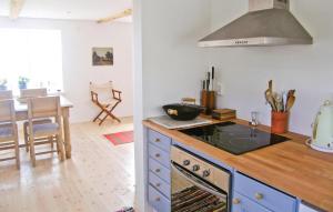 a kitchen with a stove top oven next to a table at Holiday Home Fiskarevägen Abbekås Ii in Abbekås