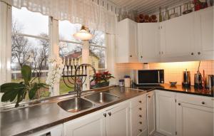 a kitchen with white cabinets and a sink and a window at 4 Bedroom Stunning Home In Färgelanda in Färgelanda