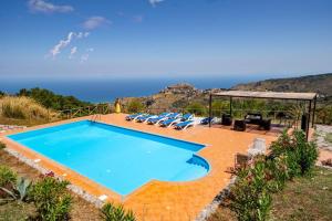 a swimming pool with chairs and a view of the ocean at La Collina dei Nebrodi in San Marco dʼAlunzio
