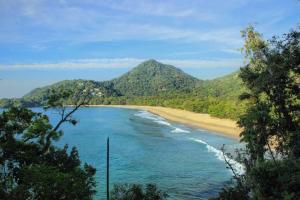 vistas a una playa con montañas en el fondo en Villa Félix Suites e Chalés, en Ubatuba