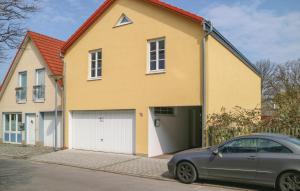 una casa amarilla con un coche aparcado delante de ella en Gorgeous Apartment In Warnemnde With Kitchen, en Warnemünde