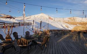 a deck with chairs and tables and a snow covered mountain at Colorado Apart Hotel in El Colorado