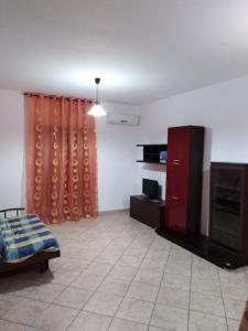 a living room with a bed and a tv and curtains at Appartamento Vibo Valentia Marina Vicino il mare in Vibo Valentia Marina