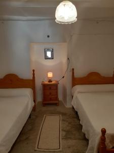 1 dormitorio con 2 camas y mesita de noche con lámpara en Casa Rocio, en Capileira