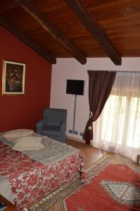 um quarto com uma cama, uma cadeira e uma televisão em La Corte Di Langa em Albaretto Della Torre 