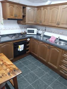 cocina con armarios de madera, fregadero y fogones en Casa Rocio, en Capileira