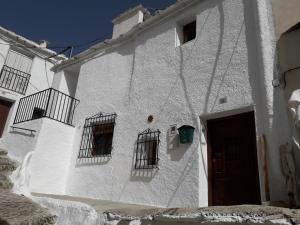 un edificio blanco con tres ventanas y una puerta en Casa Rocio, en Capileira