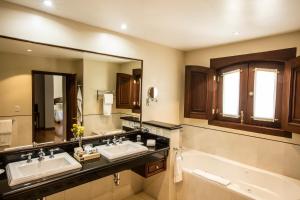 La salle de bains est pourvue de 2 lavabos, d'une baignoire et d'un miroir. dans l'établissement Villa Maria Cristina Hotel, à Guanajuato