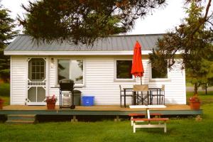 Iroquois的住宿－多蘭灣度假村木屋，一间白色的小房子,配有烧烤架和遮阳伞