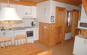 a kitchen with white appliances and a table and chairs at 3 Bedroom Awesome Home In Sysslebck in Branäs