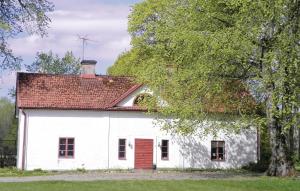 ein weißes Haus mit einer roten Tür und einem Baum in der Unterkunft Holiday Home Flishult Gård Vetlanda in Vetlanda