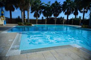 a large swimming pool with palm trees in it at Case Vacanze Ancora in Porto Empedocle