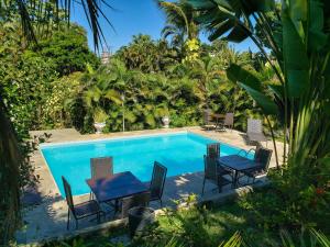 a swimming pool with chairs and a table next to it at Pousada Tropical in Arraial d'Ajuda