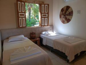 two beds in a room with a window at Pousada Tropical in Arraial d'Ajuda