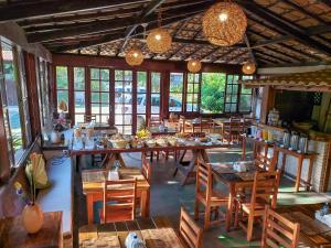 um restaurante com mesas e cadeiras de madeira e janelas em Pousada Tropical em Arraial d'Ajuda