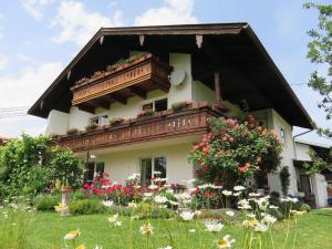 ein Haus mit einem Balkon und Blumen im Hof in der Unterkunft Ferienwohnung Auszeit in Grassau