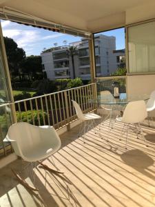 een balkon met een glazen tafel en witte stoelen bij Appartement dans résidence d'exception in Mandelieu-la-Napoule
