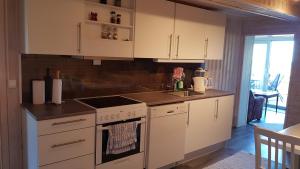 a kitchen with white cabinets and a stove top oven at Farmer Apartment in Laukvik