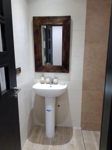 La salle de bains est pourvue d'un lavabo blanc et d'un miroir. dans l'établissement Saramica Seaside apartment, à Fnideq