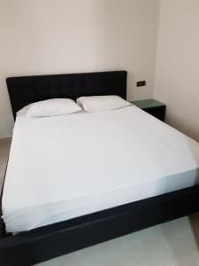 - un lit avec des draps blancs et une tête de lit noire dans l'établissement Saramica Seaside apartment, à Fnideq