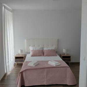 a white bedroom with a pink bed with two tables at Baixinho Guest House in Vila Praia de Âncora
