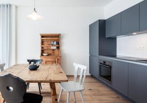 a kitchen with a wooden table and white chairs at Residence Belmonte in Collalbo