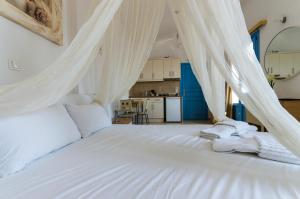 a bedroom with a white bed with white drapes at Votsalo in Astypalaia Town