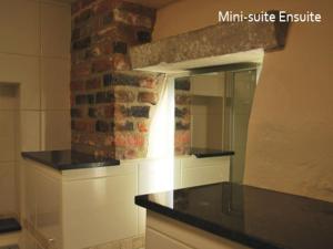 a kitchen with a mirror and a brick wall at The North Hill Hotel in Colchester