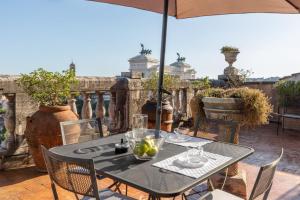 einen Tisch und Stühle auf einer Terrasse mit Sonnenschirm in der Unterkunft The Great View in Rom