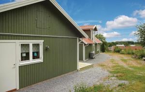 ロンネビューにあるGorgeous Home In Ronneby With House Sea Viewの白い扉と私道のある緑の建物