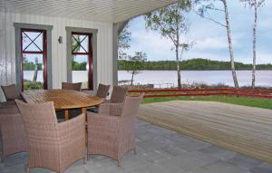 um pátio com uma mesa de madeira e cadeiras num deque em Amazing home in Vittaryd with 4 Bedrooms, Sauna and WiFi em Kvänarp