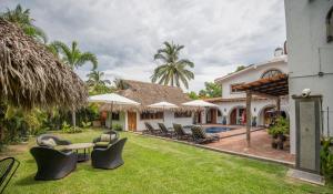 a house with a yard with chairs and umbrellas at Villa San Juan Bed&Breakfast in Nuevo Vallarta 