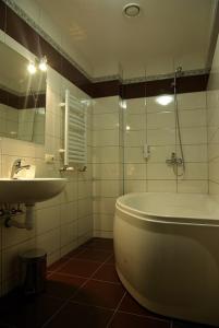 a bathroom with a sink and a tub and a mirror at Hotel Deluxe in Horodenka
