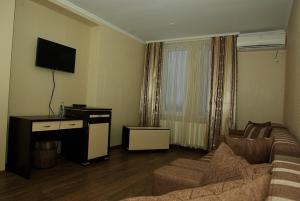 sala de estar con sofá y TV de pantalla plana en Hotel Deluxe, en Horodenka