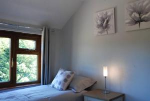 a bedroom with a bed and a window and a lamp at Hollyhock Cottage in Ashford