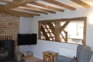 a living room with a fireplace and a tv at Hollyhock Cottage in Ashford