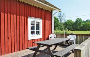 a picnic table on a deck next to a red building at 2 Bedroom Beautiful Home In Linneryd in Linneryd
