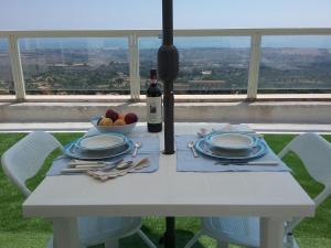 einen weißen Tisch mit einer Flasche Wein und einer Schale Obst in der Unterkunft Attico d'arte sulla Valle dei Templi in Agrigento