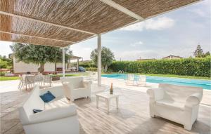 une terrasse avec mobilier blanc et une piscine dans l'établissement Beautiful Home In Comiso rg With Kitchen, à Comiso