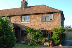 a brick house with windows and a fire hydrant at Hollyhock Cottage in Ashford