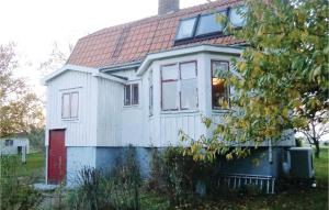 a small white house with a red door at Stunning Home In Degerhamn With Wifi in Gammalsby