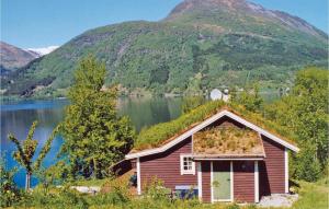 an old house on the side of a lake with a mountain at Beautiful Home In Skei I Jølster in Årdal