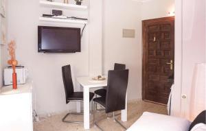 デニアにあるCozy Apartment In Denia With Swimming Poolのテーブル、椅子、壁掛けテレビが備わる客室です。