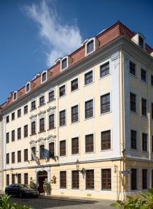 un grande edificio bianco con un'auto parcheggiata di fronte di Romantik Hotel Bülow Residenz a Dresda