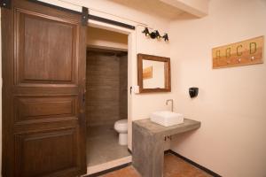 a bathroom with a toilet and a sink and a door at Cactus Hostel & Suites in Guanajuato